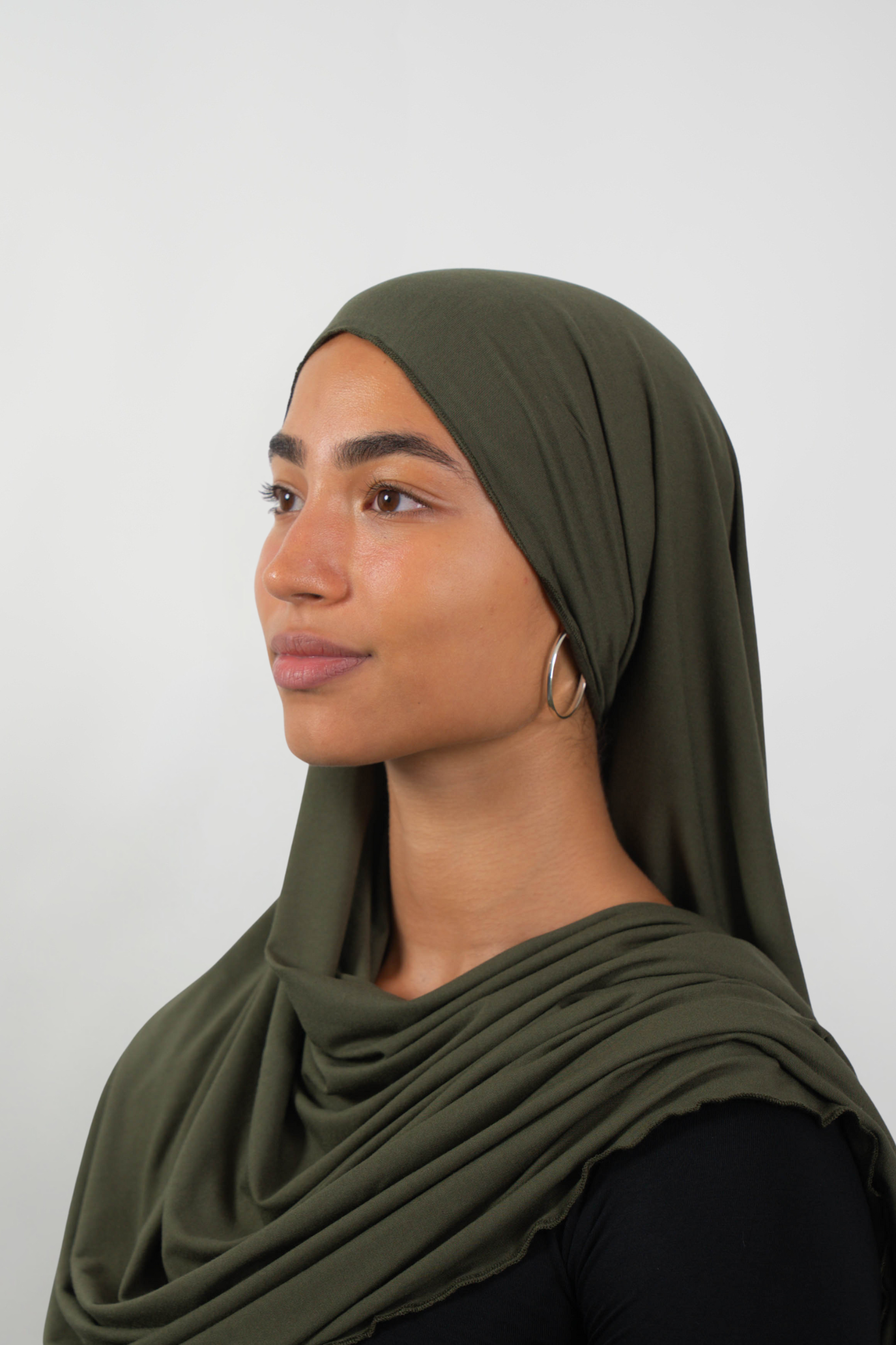 Olivfarbener Hijab aus weichem Stoff, seitliche Ansicht getragen von einer Frau – Produktbild im Online-Shop.
