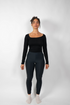 Schwarze, eng anliegende Leggings mit hohem Bund, getragen von einer Frau in einem schwarzen Langarmshirt.