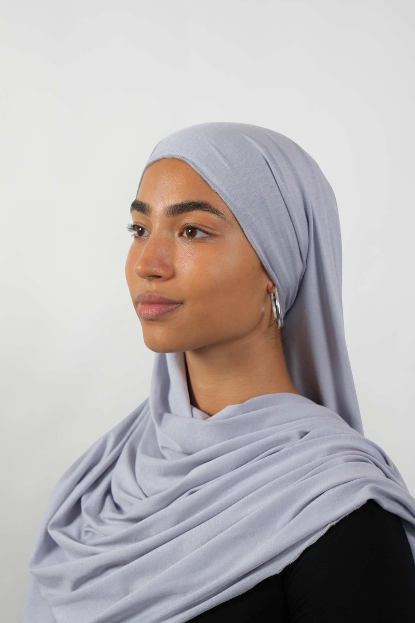Grauer Hijab aus weichem Stoff, seitliche Ansicht getragen von einer Frau – Produktbild im Online-Shop.