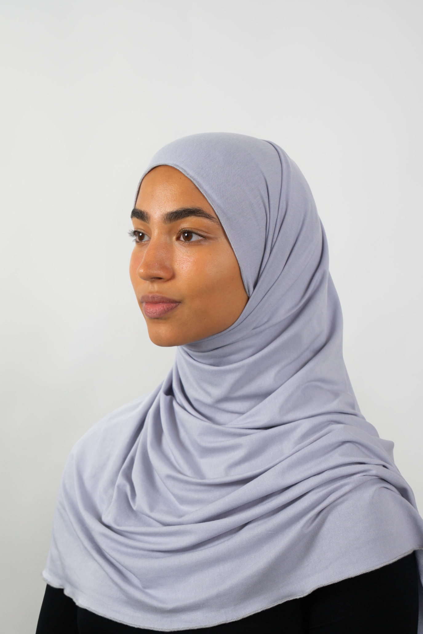 Grauer Hijab aus weichem Stoff, seitliche Ansicht getragen von einer Frau – Produktbild im Online-Shop.