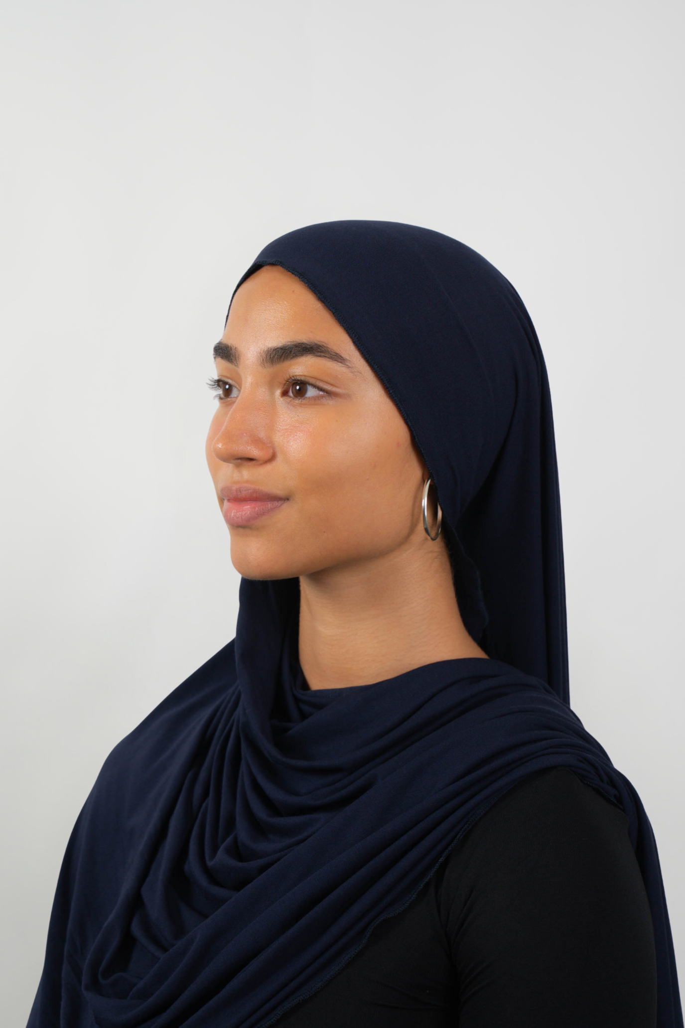 Dunkelblauer Hijab aus weichem Stoff, seitliche Ansicht getragen von einer Frau – Produktbild im Online-Shop.