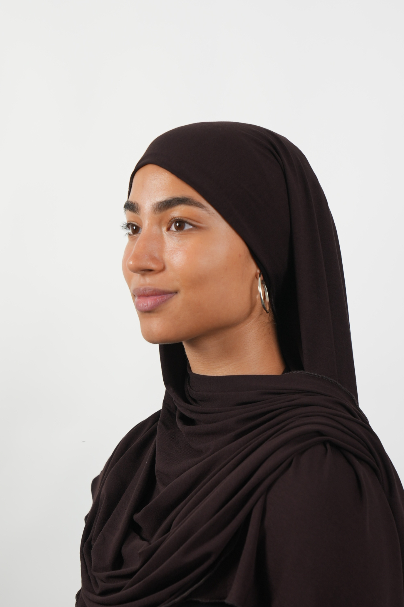 Brauner Hijab aus weichem Stoff, seitliche Ansicht getragen von einer Frau – Produktbild im Online-Shop.