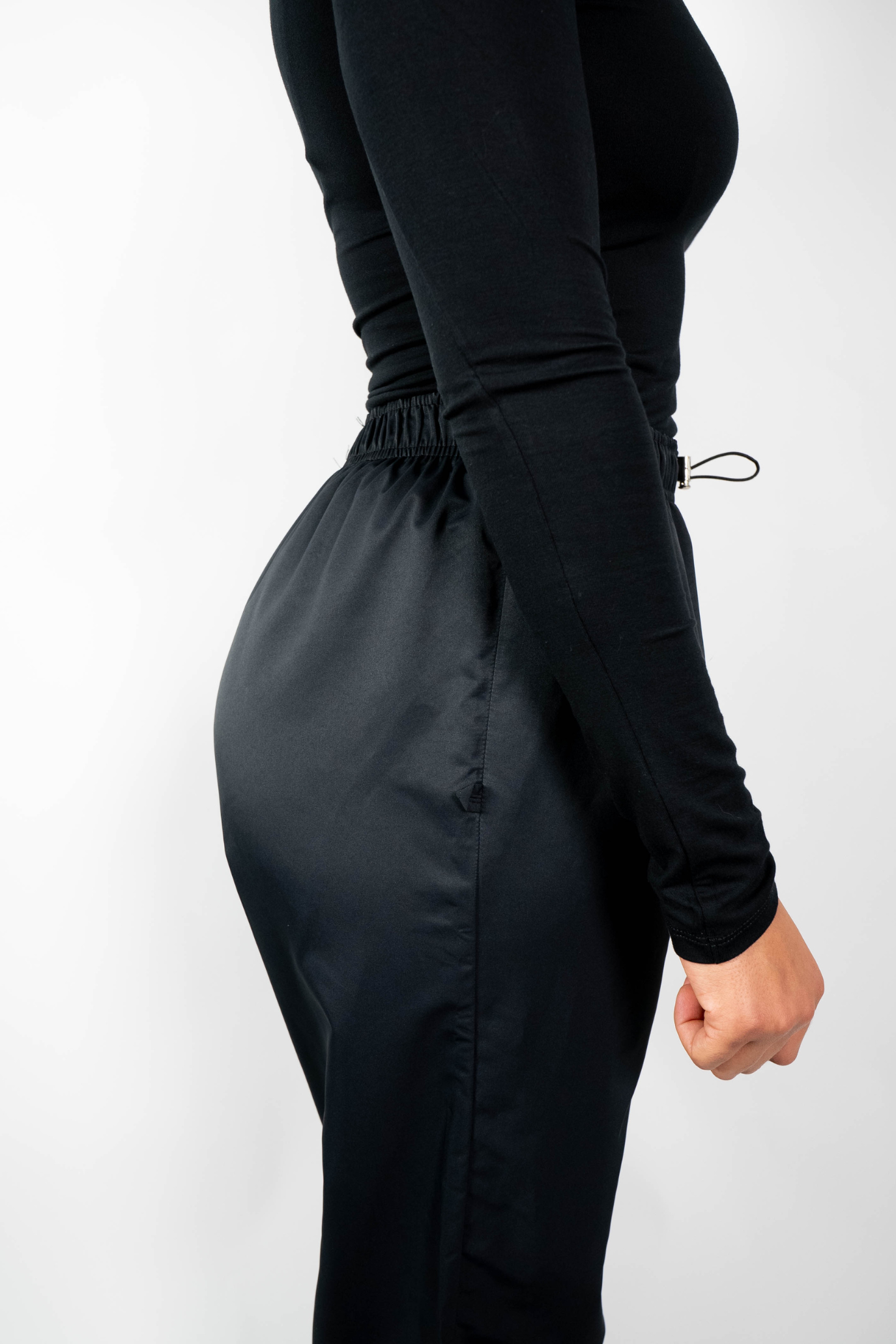 Nahaufnahme der schwarzen, lockeren Badehose von der Seite, die den elastischen und gerafften Bund mit Taillenzug zeigt.