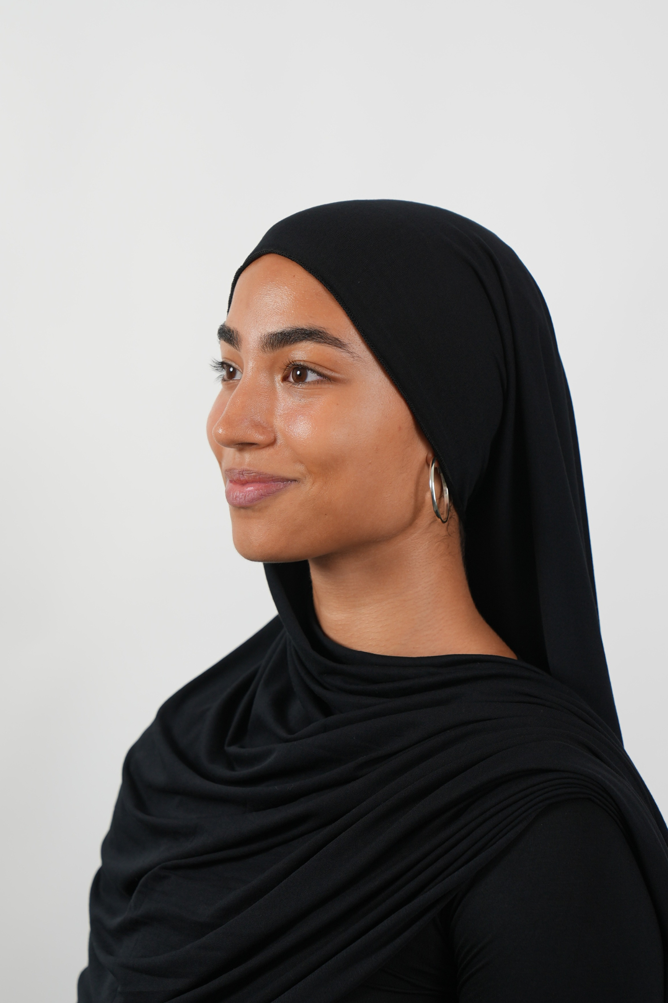 Schwarzer Hijab aus weichem Stoff, seitliche Ansicht getragen von einer Frau – Produktbild im Online-Shop.