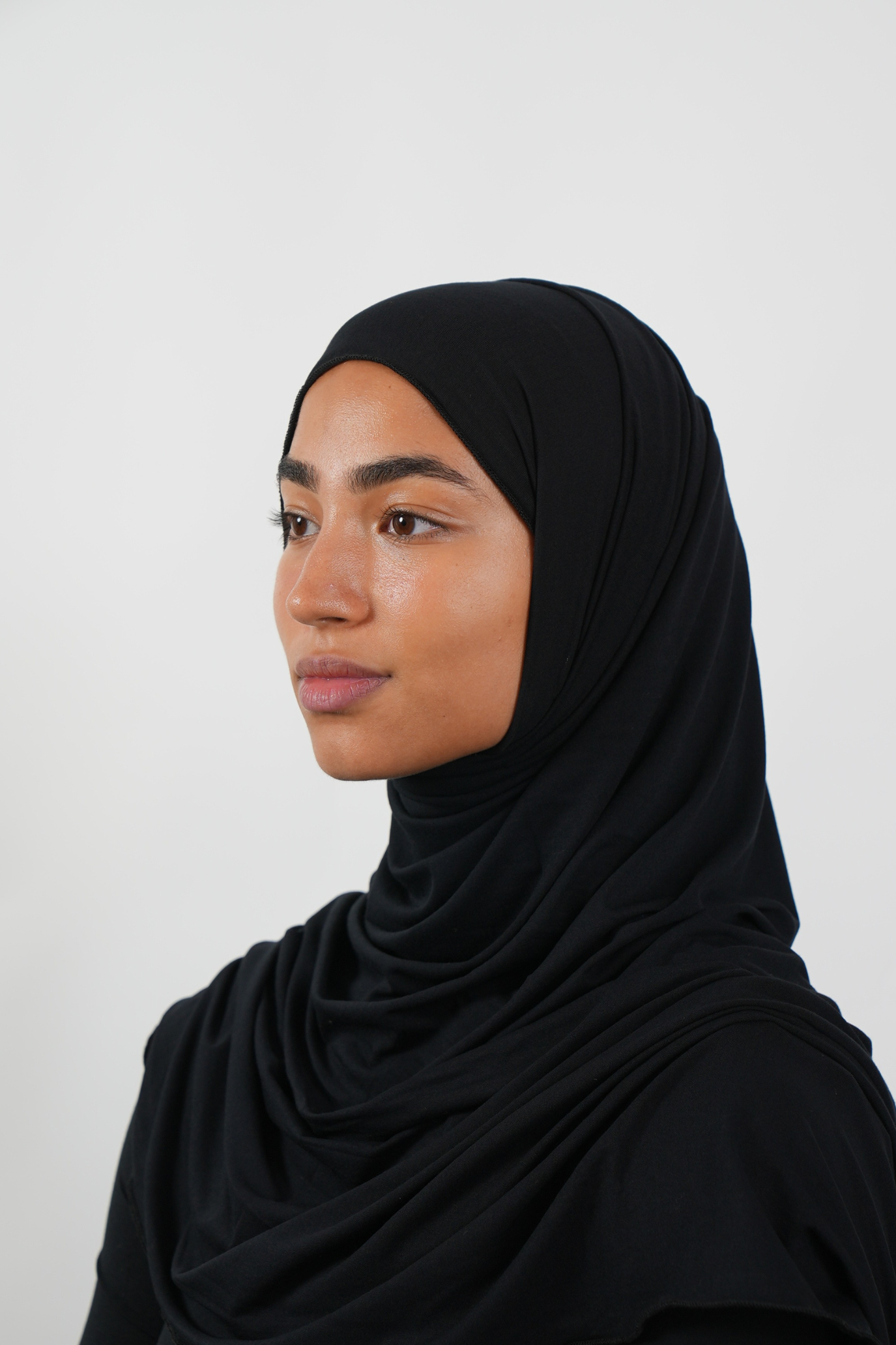 Schwarzer Hijab aus weichem Stoff, seitliche Ansicht getragen von einer Frau – Produktbild im Online-Shop.