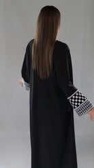 Schwarze Abaya mit traditionellen palästinensischen Mustern an den Ärmeln, elegant und kulturell inspirierend.