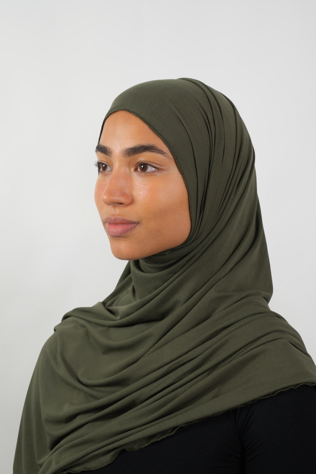 Olivfarbener Hijab aus weichem Stoff, seitliche Ansicht getragen von einer Frau – Produktbild im Online-Shop.