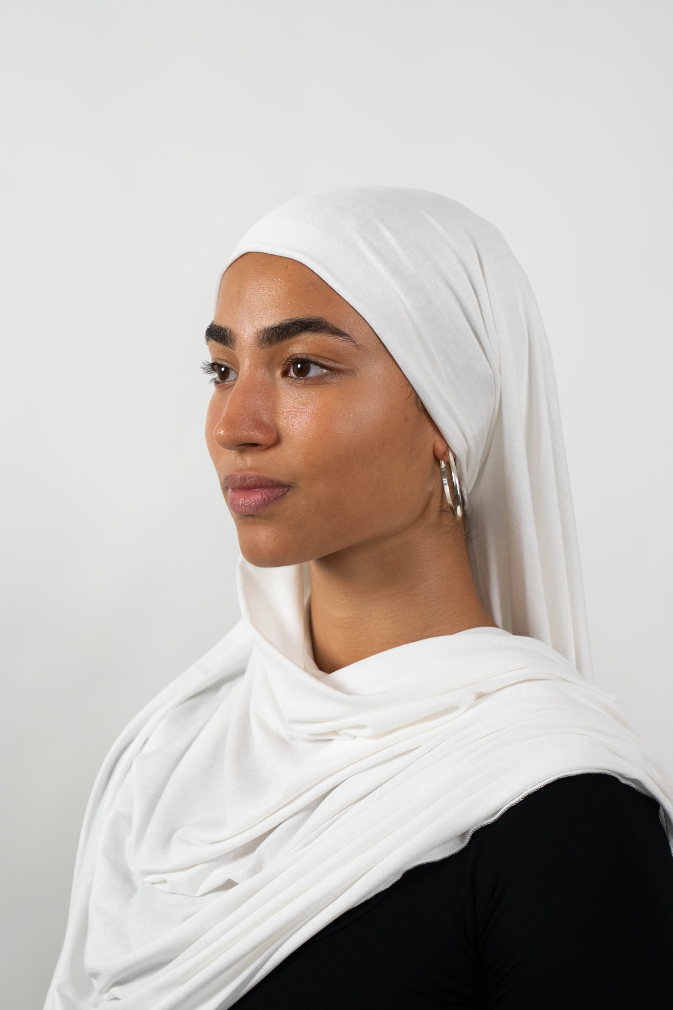 Weißer Hijab aus weichem Stoff, seitliche Ansicht getragen von einer Frau – Produktbild im Online-Shop.