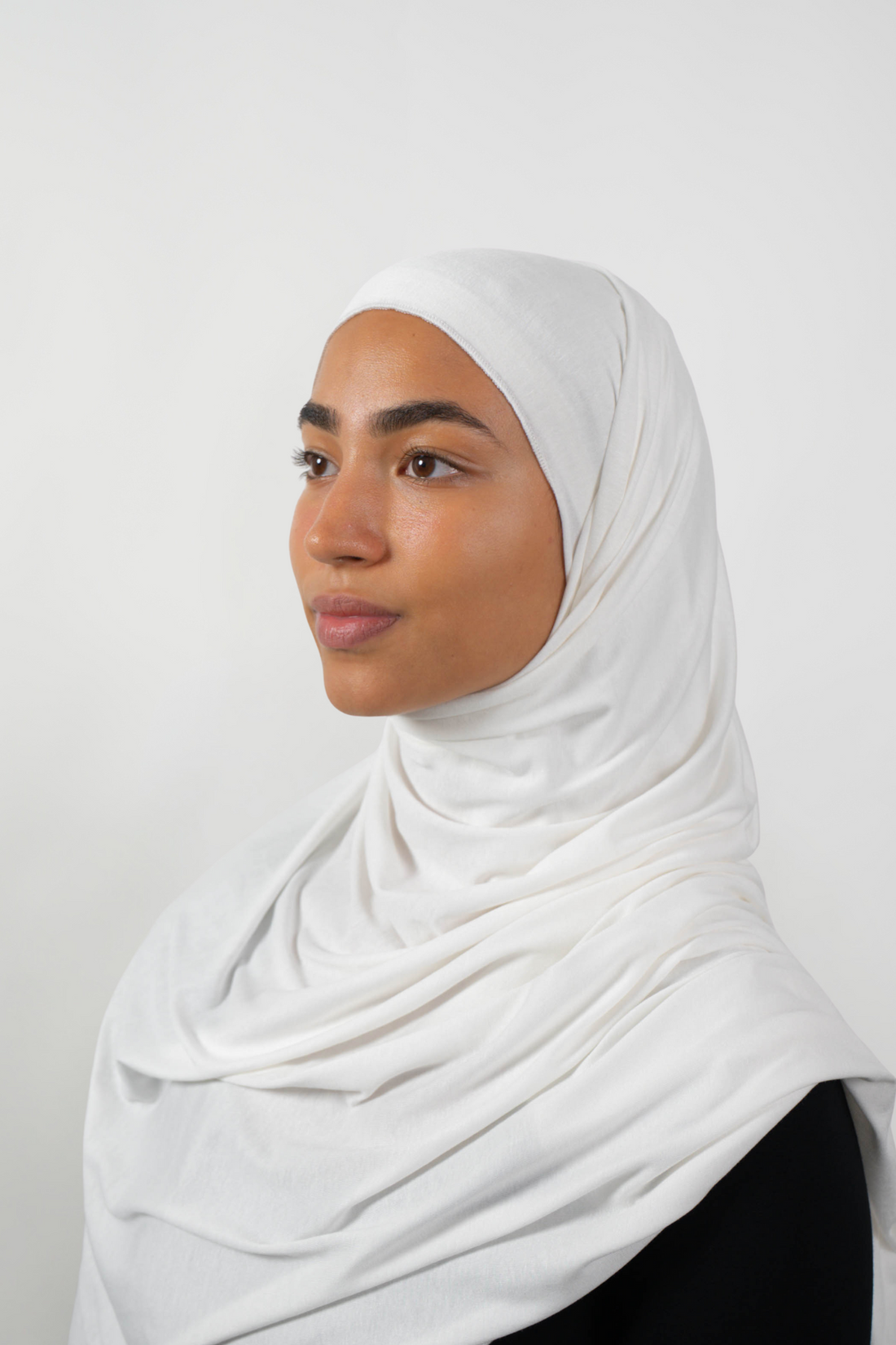 Weißer Hijab aus weichem Stoff, seitliche Ansicht getragen von einer Frau – Produktbild im Online-Shop.