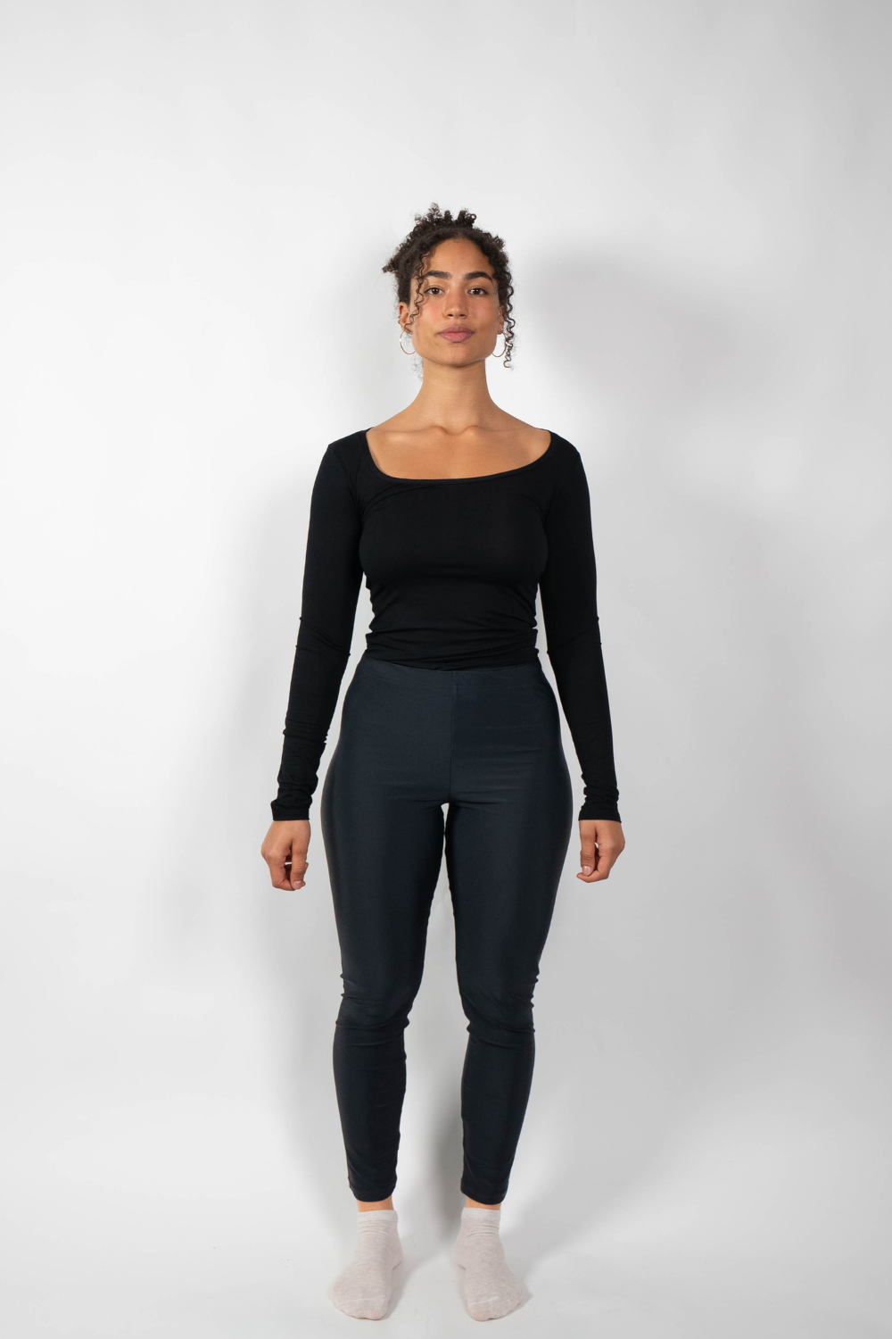 Schwarze, eng anliegende Leggings mit hohem Bund, getragen von einer Frau in einem schwarzen Langarmshirt.