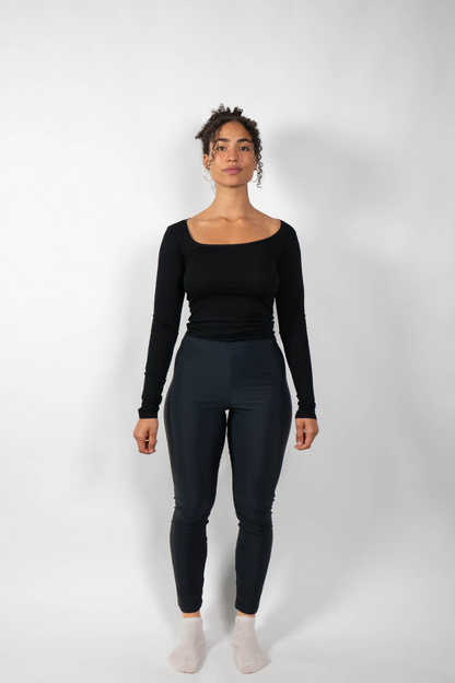 Schwarze, eng anliegende Leggings mit hohem Bund, getragen von einer Frau in einem schwarzen Langarmshirt.