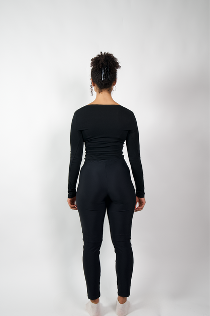 Rückenansicht einer Frau in schwarzen, eng anliegenden Leggings und einem schwarzen Langarmshirt.