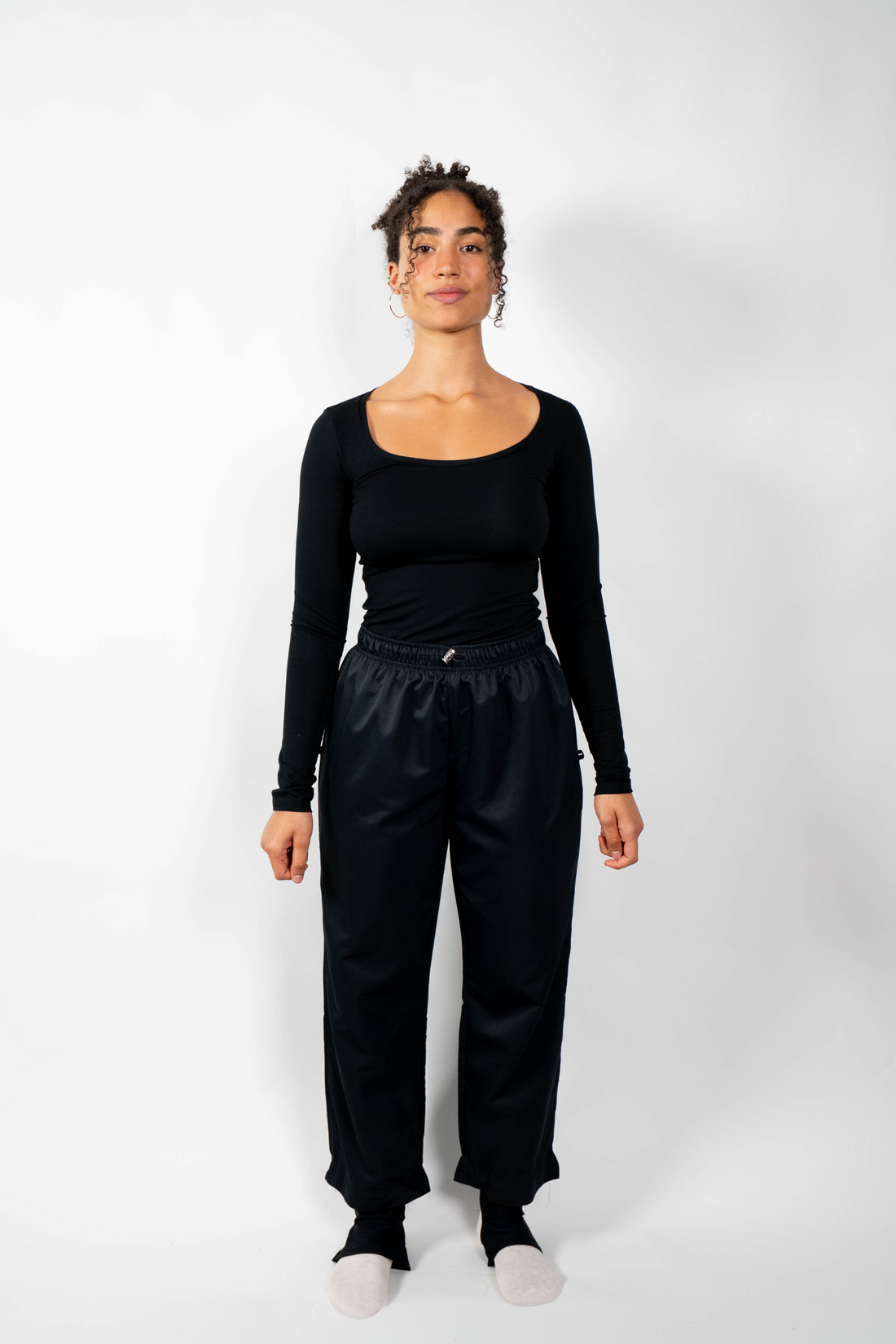 Schwarze, lockere Sporthose (Badehose) mit elastischem Bund und Taillenzug, getragen von einer Frau in einem schwarzen Langarmshirt.
