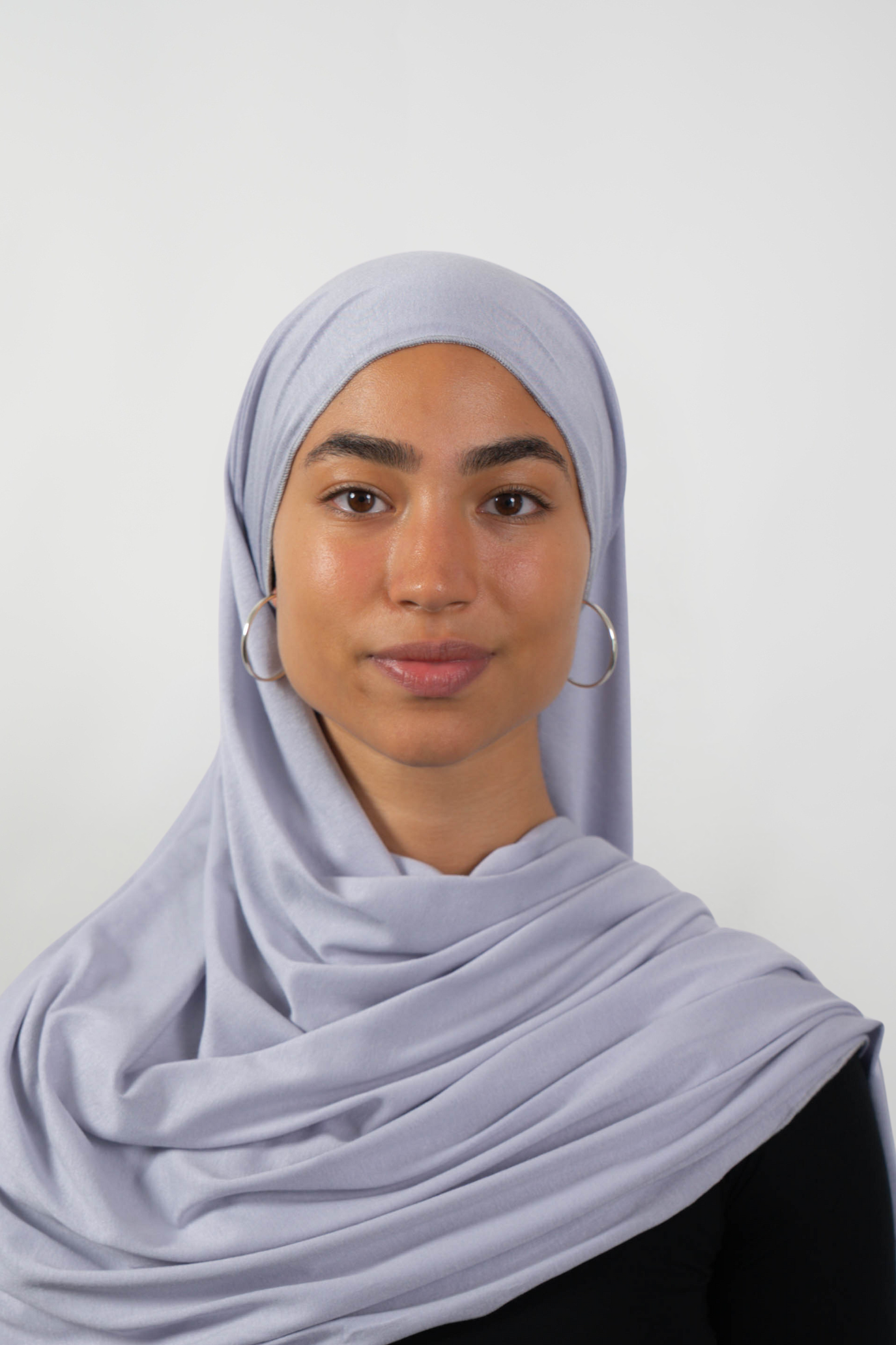 Grauer Hijab aus weichem Stoff, getragen von einer Frau – Produktbild im Online-Shop.