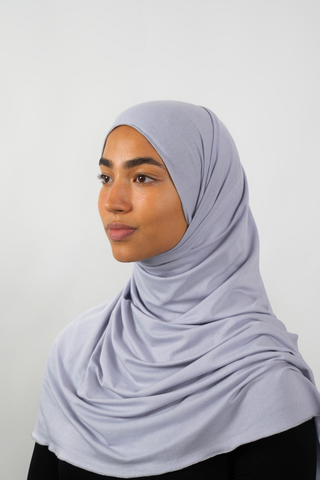 Grauer Hijab aus weichem Stoff, seitliche Ansicht getragen von einer Frau – Produktbild im Online-Shop.