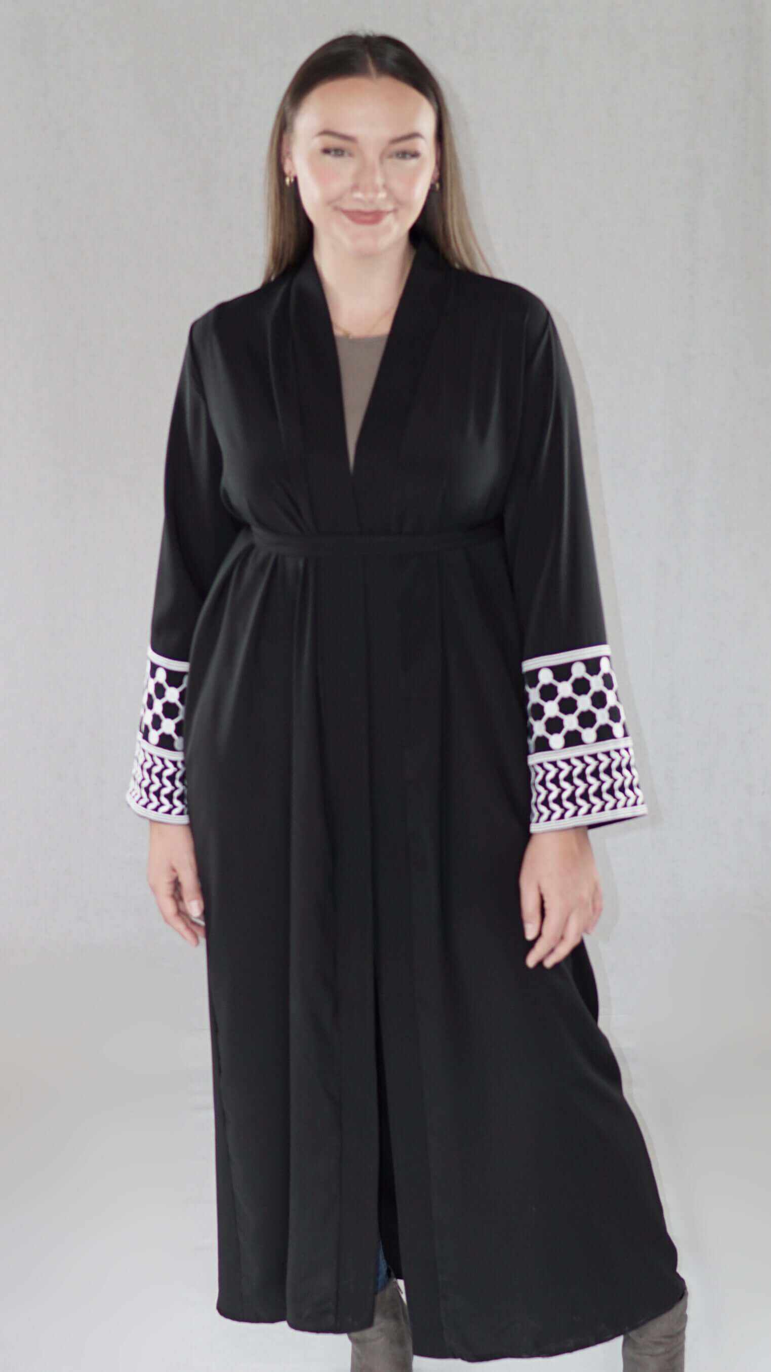 Schwarze Abaya mit palästinensischem Design und traditionellen Mustern, getragen von einer lächelnden Frau.