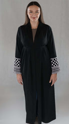 Schwarze Abaya mit palästinensischem Design und detaillierten Ärmeln, präsentiert von einer Frau.