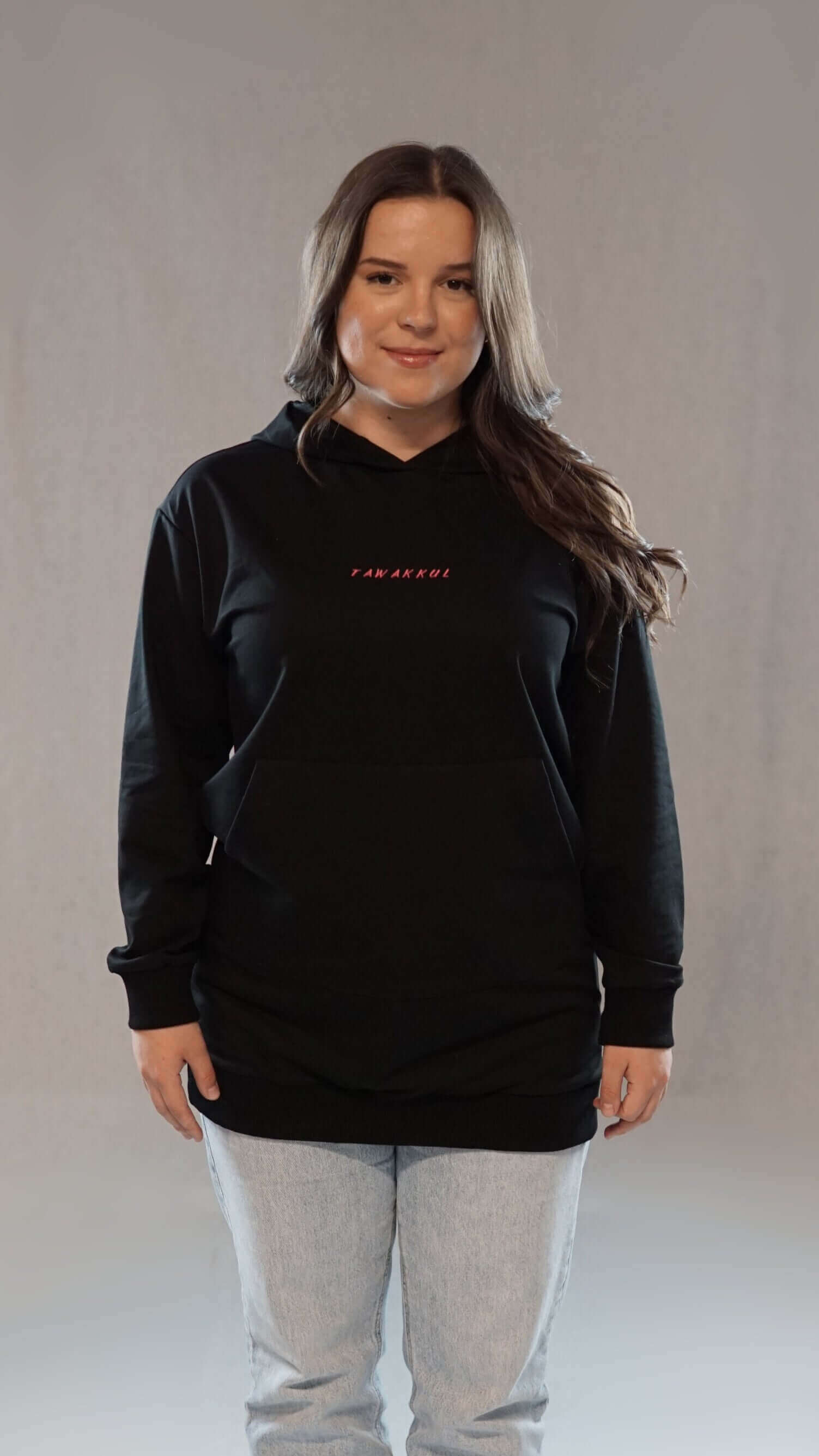 Woman wearing black Damen Hoodie Tawakkul, showcasing comfort and spiritual style with long fit.