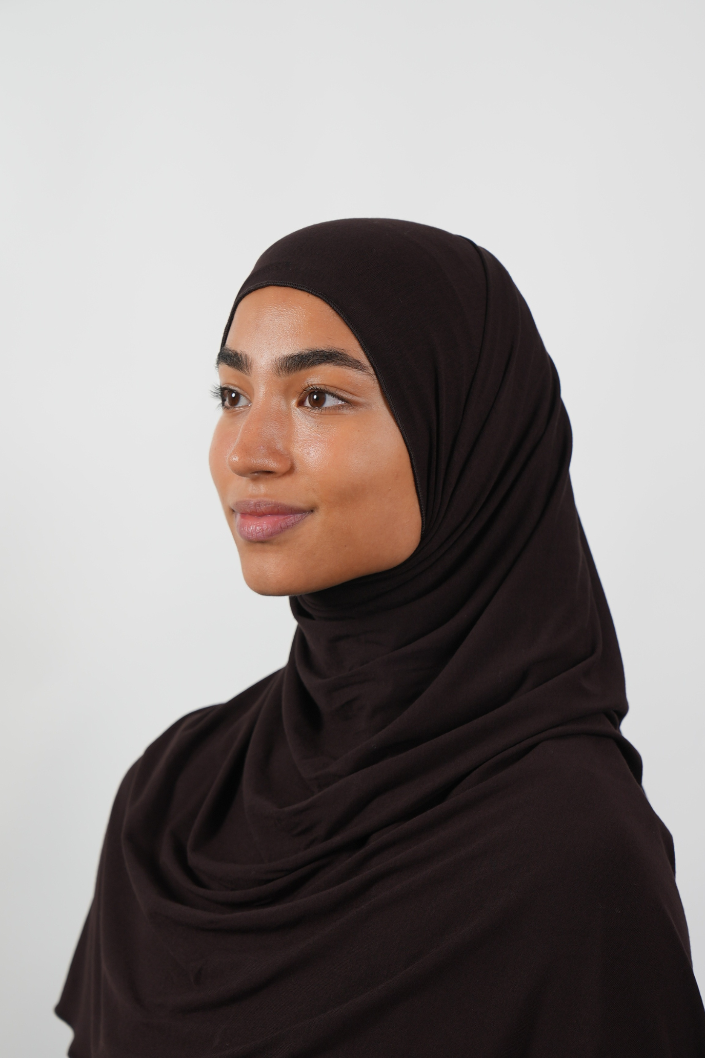 Brauner Hijab aus weichem Stoff, seitliche Ansicht getragen von einer Frau – Produktbild im Online-Shop.