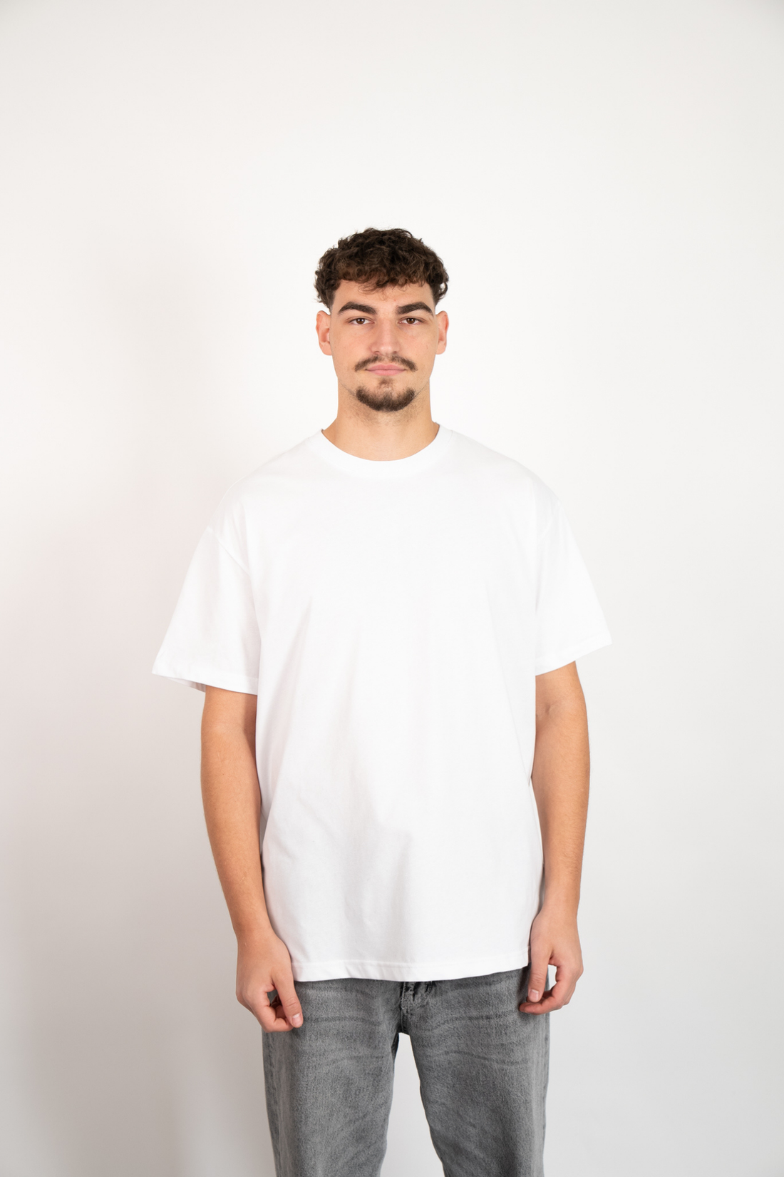 Weißes Oversize T-Shirt aus 100% Baumwolle mit Rundhalsausschnitt, getragen von einem Mann.