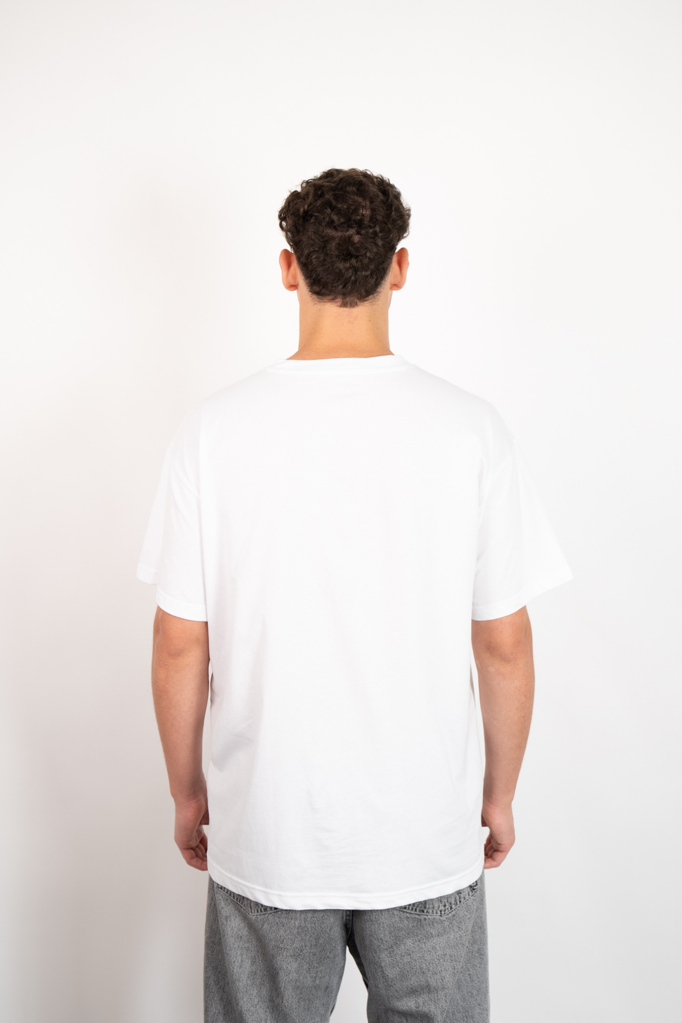 Weißes Oversize T-Shirt aus 100% Baumwolle mit Rundhalsausschnitt, getragen von einem Mann in Rückenansicht.