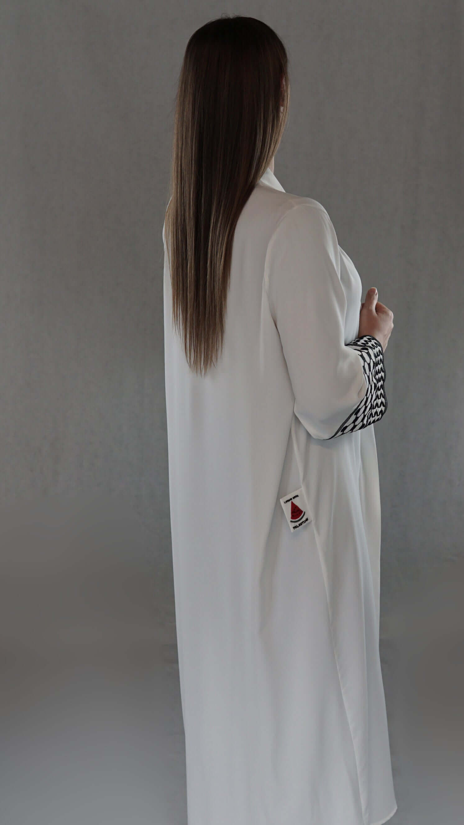 Elegante weiße Abaya mit palästinensischem Design, sichtbarem Olivenblattmuster und modernem Schnitt, getragen von Model.