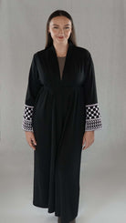 Schwarze Abaya mit traditionellen palästinensischen Mustern an den Ärmeln, elegantes Design und symbolische Bedeutung.