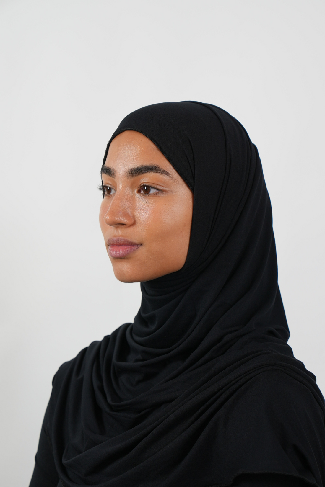 Schwarzer Hijab aus weichem Stoff, seitliche Ansicht getragen von einer Frau – Produktbild im Online-Shop.