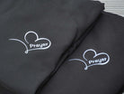 Black hoodies featuring a heart design with the word "Prayer" embroidered in white.