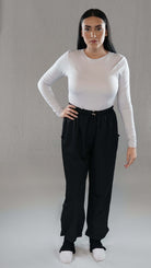 Model wearing a white long-sleeve top and black trousers, showcasing a stylish and comfortable outfit.