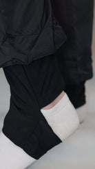 Close-up of black burkini pants with a layered design, showcasing a white sock on a model's foot.