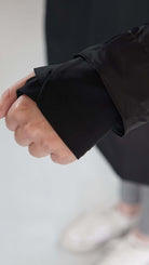 Hand wearing a black swim tunic, showcasing sleeve detail for comfort and functionality.