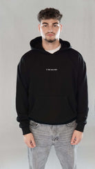 Man wearing black oversize hoodie with "Tawakkul" inscription on the chest, symbolizing deep faith and spiritual trust.