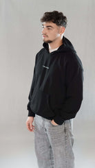 Man wearing black oversize hoodie with "Tawakkul" text on front, embodying faith and spiritual confidence.