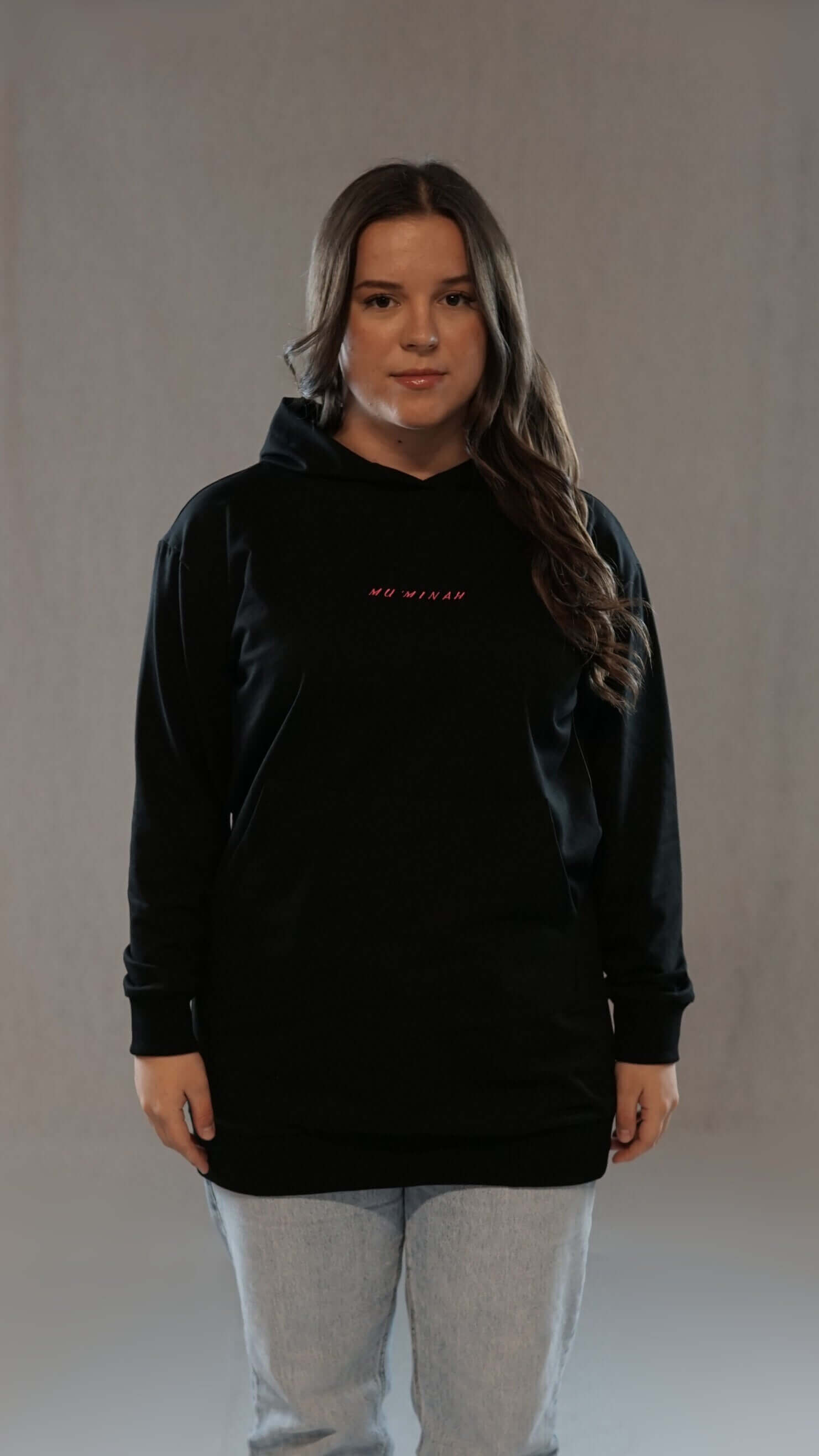 Woman wearing a black Muminah Damen Hoodie with subtle design, embodying modern style and comfort.