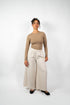 Weite, cremefarbene (oder hellbeige) Hose im Culotte- oder Marlene-Stil aus weichem Material mit elastischem Bund, getragen von einer Frau.