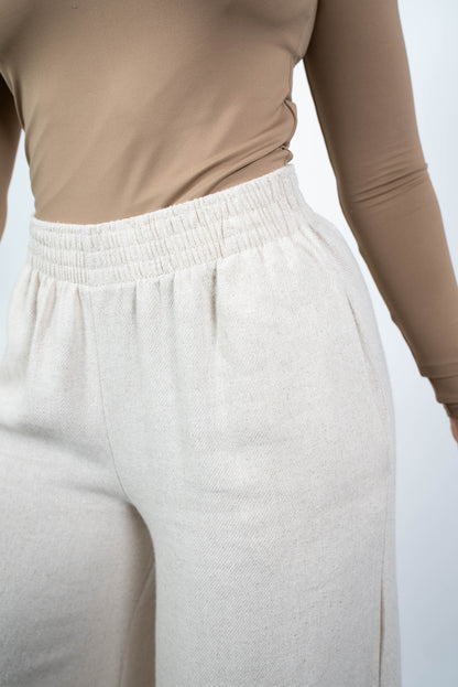 Nahaufnahme des Bundes der cremefarbenen, weiten Marlene-Hose, die den elastischen und gerafften Bund sowie die Struktur des weichen Stoffes zeigt.