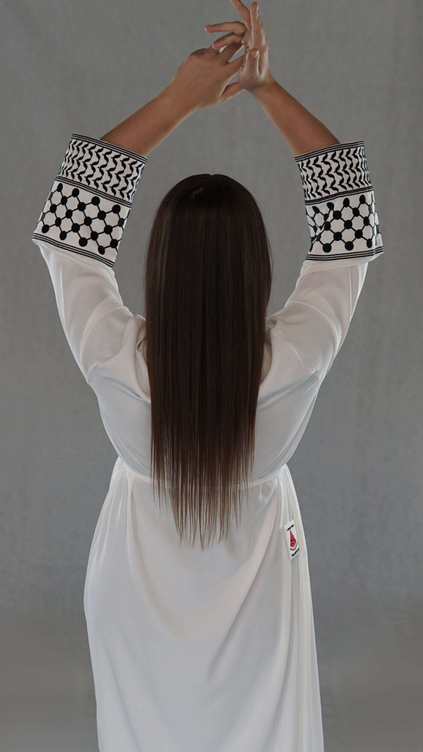 Model showcasing the back of a white Abaya with traditional Palestinian patterns on the sleeves.